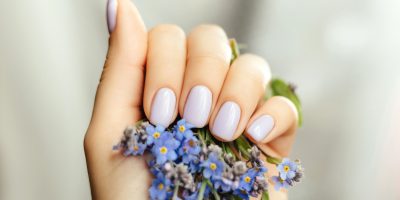 Beautiful purple manicure on a milky background with flowers.